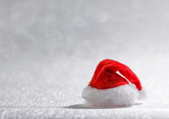 Ein kleiner roter Weihnachtsmannhut mit weißer Borte steht im Schnee.